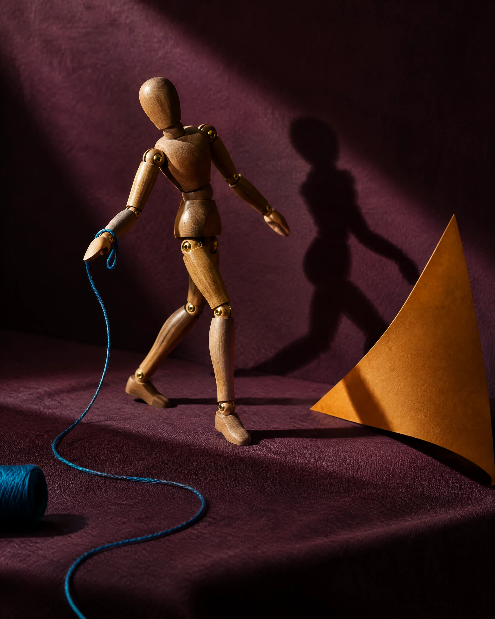 Wooden articulated figure casting a stage shadow